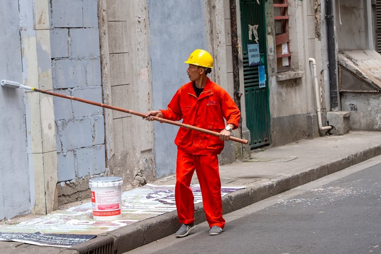 Commercial painter in workwear painting a building wall